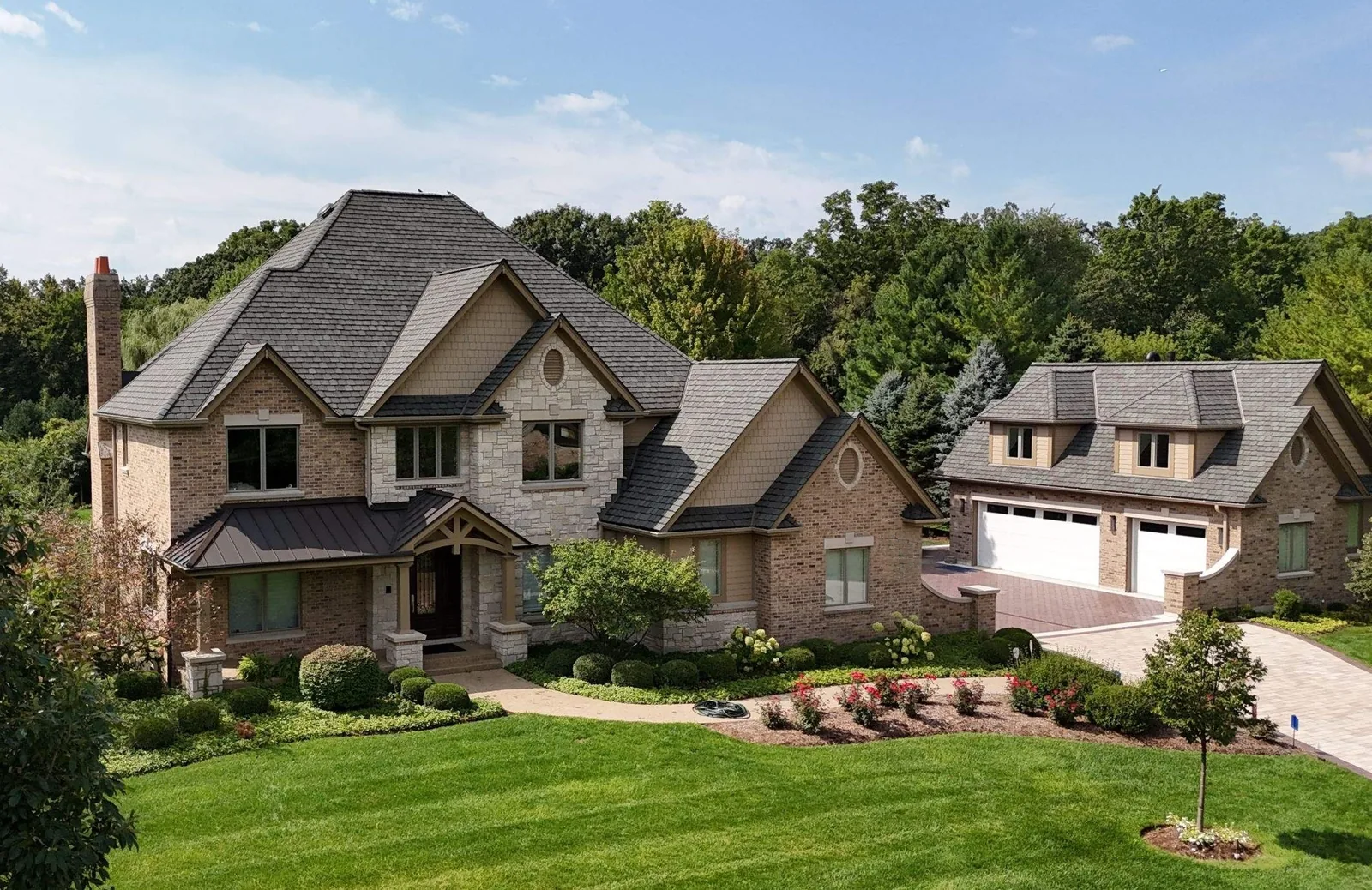 Two-story brick and stone home and detached garage with a new slate roof and standing seam metal porch roof in St. Charles, IL