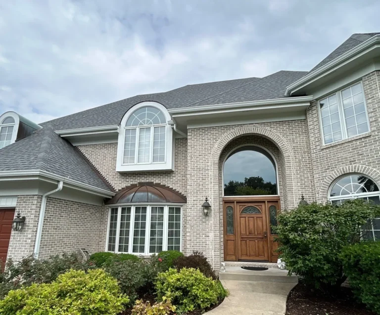 Front view of a Naperville, IL luxury home with a replaced dark hip roof, copper-toned trim and a two-story entry