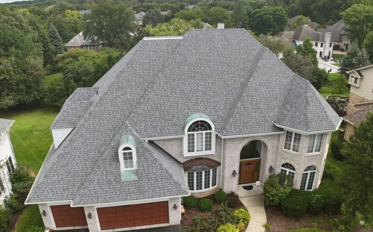 Aerial view of a brick home in Naperville, IL with a new gray architectural shingle roof and copper dormer accents