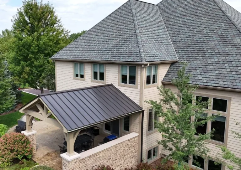 Brick and stone home in St. Charles, IL with a slate roof and a dark bronze standing seam metal porch roof