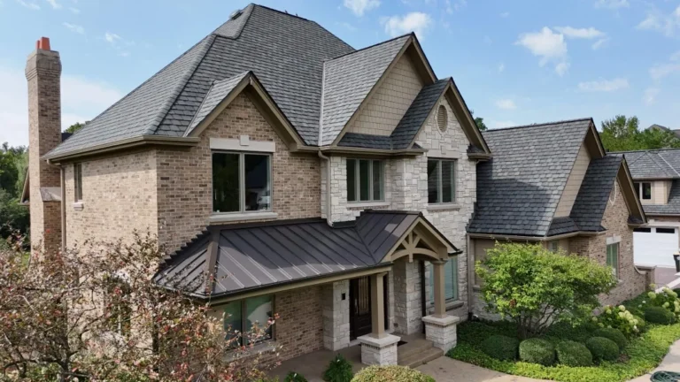 Brick and stone home in St. Charles, IL with a slate roof and a dark bronze standing seam metal porch roof