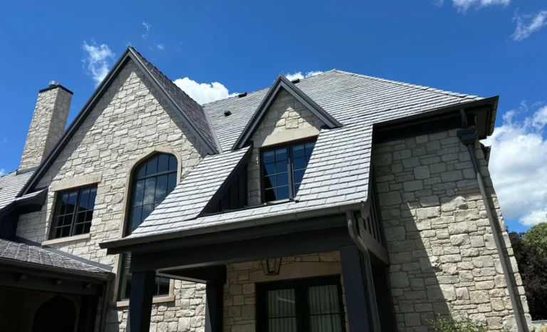 Gray slate roof with steep gables and dormers on a stone Tudor-style home in Naperville, IL