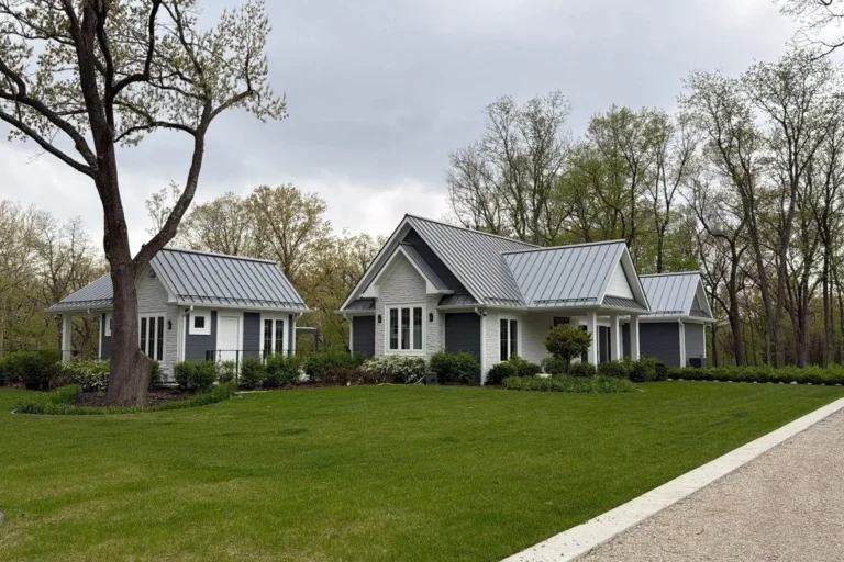 Main home, guesthouse and garage with matching gray standing seam metal roofs on a wooded property in Plano, IL