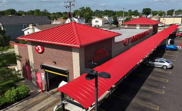 Red standing seam metal roofs and a curved metal vacuum canopy on a car wash in Stone Park, IL